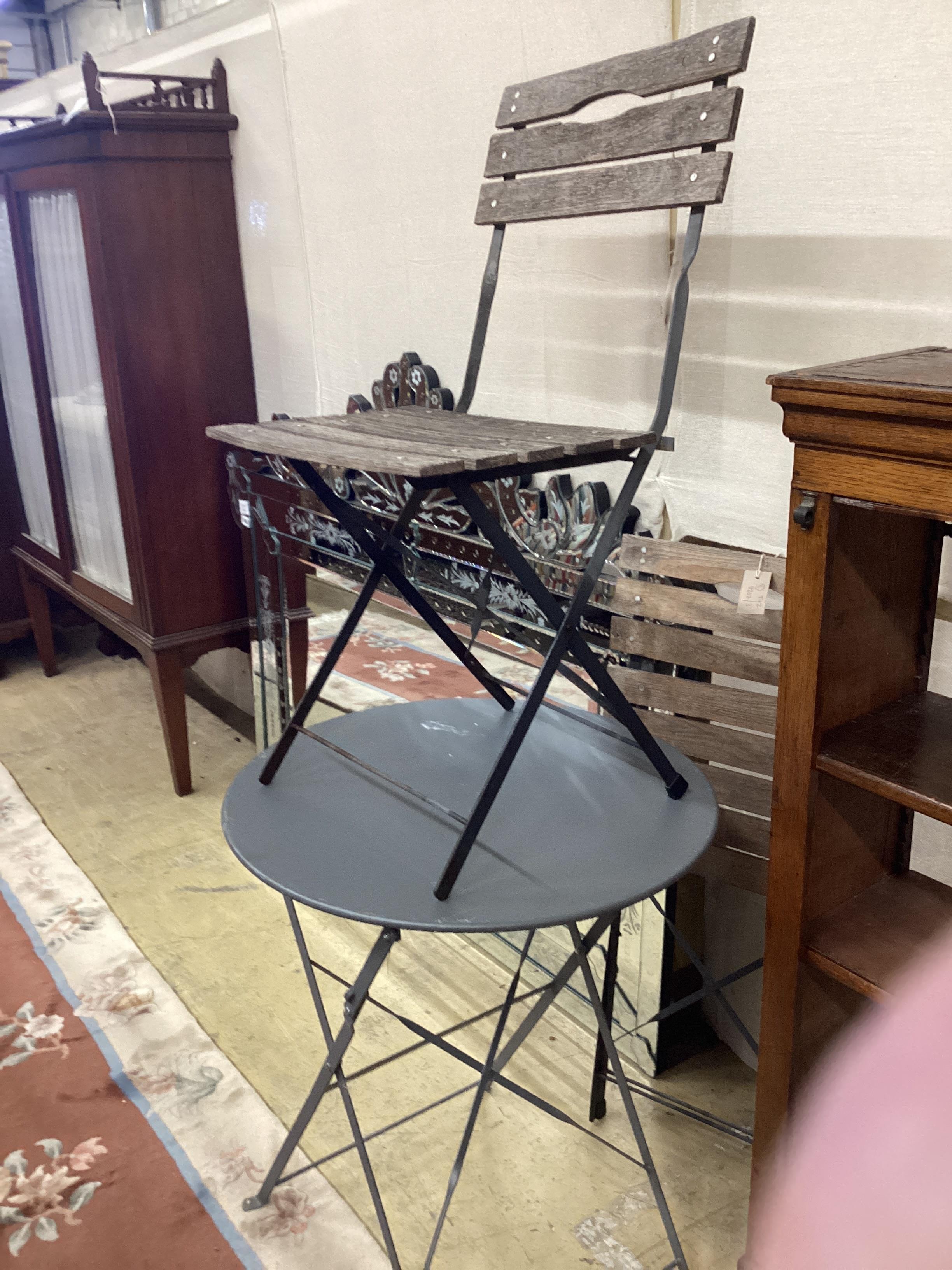A painted wrought iron circular garden table, diameter 59cm, height 72cm and two slatted folding chairs